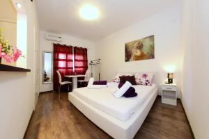 a bedroom with a large white bed and a table at Apartments Maruna Self check-in in Zadar