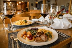 Hotel und Gasthaus Bad Gonten في Gonten: طاولة مع طبقين من الطعام وكؤوس النبيذ