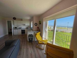 a living room with a couch and a kitchen with a window at Coastal Apartment Tramore in Waterford