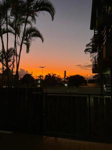 um pôr-do-sol atrás de uma cerca com uma palmeira em Canto da Ilha em Florianópolis