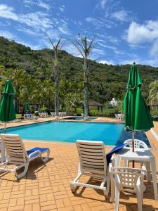 uma piscina com duas espreguiçadeiras e um guarda-sol verde em Canto da Ilha em Florianópolis