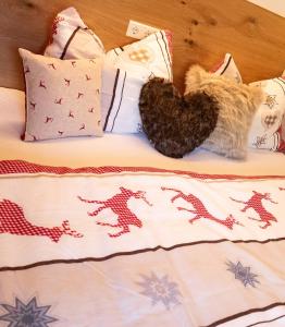 a bed with a heart and pillows on it at Alpenstern Apartment Montafon in Sankt Gallenkirch