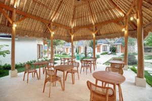 a restaurant with tables and chairs under a straw roof at Two Bedroom Villa in Bingin Beach in Uluwatu