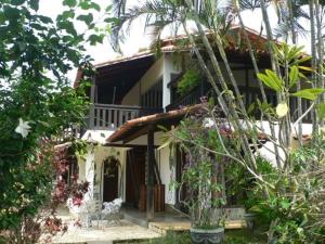 a white house with a porch and some plants at Hotel Eco Sítio Nosso Paraíso in Saquarema