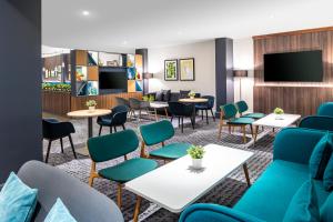 een wachtkamer met tafels en stoelen en een flatscreen-tv bij Holiday Inn Leicester City, an IHG Hotel in Leicester