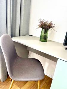 een bureau met een stoel en een vaas met bloemen bij Люкс апартаменти в затишному ЖК бізнес класу in Kiev