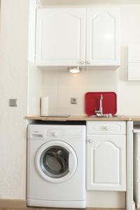 eine weiße Küche mit einer Waschmaschine und einem Waschbecken in der Unterkunft T2 Proche Capelan -parking privé gratuit - wifi in Bandol