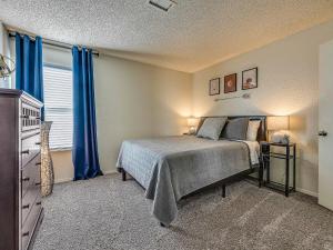 a bedroom with a bed and a window with blue curtains at OU Sooner, Pool & Gym, BBQ, Netflix, 100mb Internet, LG Washer & Dryer, Close to OU! in Norman