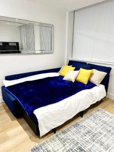 uma grande cama azul com almofadas amarelas num quarto em 1 Bed Apartment near Old Trafford with free car park em Manchester