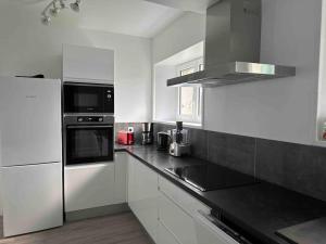 a kitchen with white cabinets and a black counter top at Le Relais Drogon in Silli-en-Gouffern