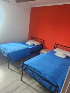 two beds in a room with a red wall at fiume veneto 1 in Bannia