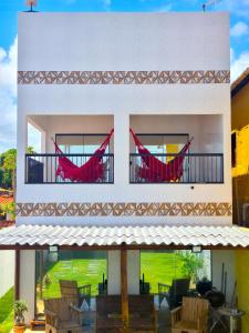 une maison blanche avec des chaises rouges sur le balcon dans l'établissement B&B Pousada Swiss Residence, à Aquiraz