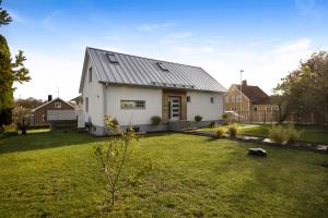 una casa blanca con techo de metal en un patio en Hyr villa i Stenhuggeriet nära till både hav och golf, en Halmstad