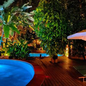 a swimming pool in a resort with a tree at alua pousada ventos de camburi in Camburi