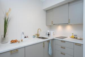 a white kitchen with white cabinets and a sink at Fortune Apartments - River view, Contactless in Tartu
