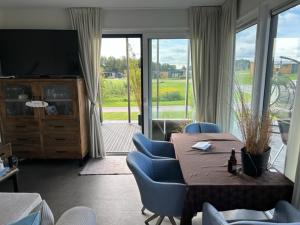 ein Wohnzimmer mit einem Tisch, Stühlen und einem TV in der Unterkunft Seaside Beach House Chalet - Seeparx Süsel in Süsel