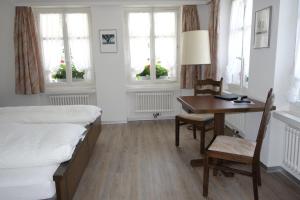 a bedroom with two beds and a desk and a table at Gasthof Löwen in Melchnau