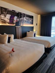 2 Betten in einem Hotelzimmer mit einer roten Blume darauf in der Unterkunft Grand Hotel Times Levis in Lévis