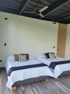 2 Betten in einem Zimmer mit weißen Wänden und Holzböden in der Unterkunft MILAVES in La Tebaida