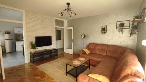 ein Wohnzimmer mit einem braunen Ledersofa und einer Küche in der Unterkunft Apartman Majur in Slavonski Brod