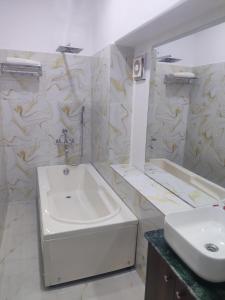 Baño blanco con lavabo y espejo en The corridor inn en Calcuta