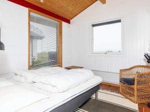 Ce lit se trouve dans un dortoir doté d'une fenêtre et d'une chaise. dans l'établissement Holiday home Bindslev XVII, à Bindslev