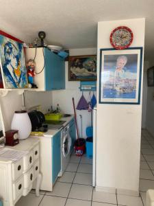 eine Küche mit blauen Schränken und einer Uhr an der Wand in der Unterkunft T 2 cosy bord de mer in Le Barcarès
