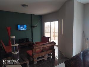 een woonkamer met een bank en een tv aan de muur bij Estancia Spondylus in San Lorenzo