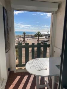einen Balkon mit einem Tisch und Strandblick in der Unterkunft T 2 cosy bord de mer in Le Barcarès