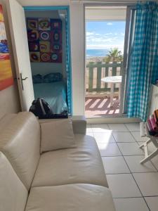 ein Wohnzimmer mit Couch und Blick aufs Meer in der Unterkunft T 2 cosy bord de mer in Le Barcarès