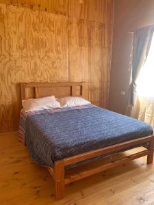 Bett in einem Zimmer mit einer Holzwand in der Unterkunft Cabañas Guanaqueros Arriendo Diario in Guanaqueros