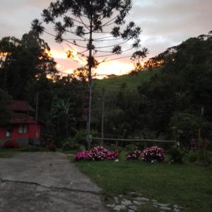 una puesta de sol de una casa con flores en el patio en Casa da floresta, en Bocaina de Minas