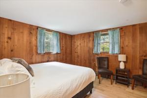 a bedroom with wooden walls and a bed and a chair at Evergreen Chalet in Stowe
