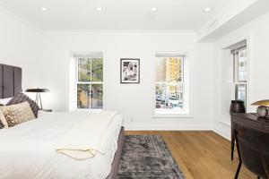 a white bedroom with a bed and two windows at Luxurious 5 BR Townhouse in New York