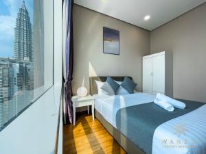 um quarto com uma cama e uma grande janela em Soho Suites KLCC by Wakely Kuala Lumpur em Kuala Lumpur