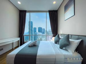Soho Suites KLCC by Wakely Kuala Lumpur في كوالالمبور: غرفة نوم بسرير مع اطلالة على المدينة