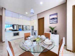 Soho Suites KLCC by Wakely Kuala Lumpur في كوالالمبور: مطبخ وغرفة طعام مع طاولة وكراسي زجاجية