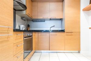 uma cozinha com armários de madeira e um lavatório em Grand Canal 2 Bedroom Flat em Dublin