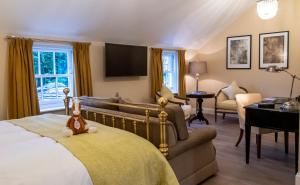 um quarto com uma cama, um sofá e uma televisão em Bedford Lodge Hotel & Spa em Newmarket