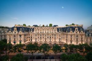 un grand bâtiment avec des arbres devant dans l'établissement The Peninsula Paris, à Paris