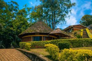 a house with a thatched roof and a brick path at Peace Guest House in Muhari