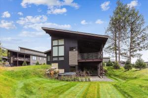 una casa negra en una colina con un patio en Streamside Lodge, en Stowe