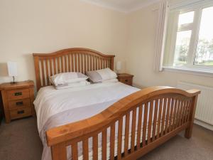 a bedroom with a wooden bed with white sheets and pillows at Dunira in Mallaig
