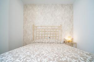 1 dormitorio con 1 cama con colcha blanca en Piso Torno, en Sanlúcar de Barrameda
