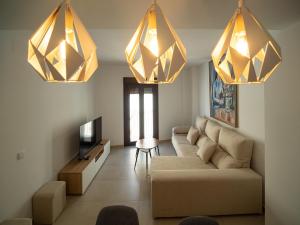 sala de estar con sofá y 2 lámparas de araña en Piso Torno, en Sanlúcar de Barrameda
