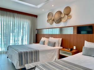 a hotel room with two beds and a window at Hotel Paradiso del Sol in Cabo Frio