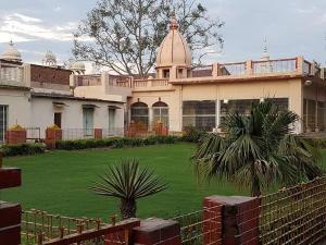 Shree Krishna Bhakti Ashram في فريندافان: منزل أمامه حديقة خضراء