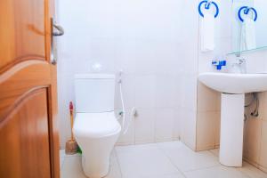 a bathroom with a white toilet and a sink at Peace Guest House in Muhari