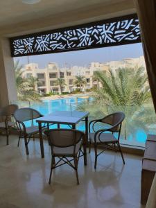 una mesa y sillas con vistas a la piscina en Mangroovy 2BR with roof en Hurghada