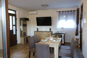 a dining room with a table and chairs and a television at Holiday Home Rajf in Donji Koncovčak
